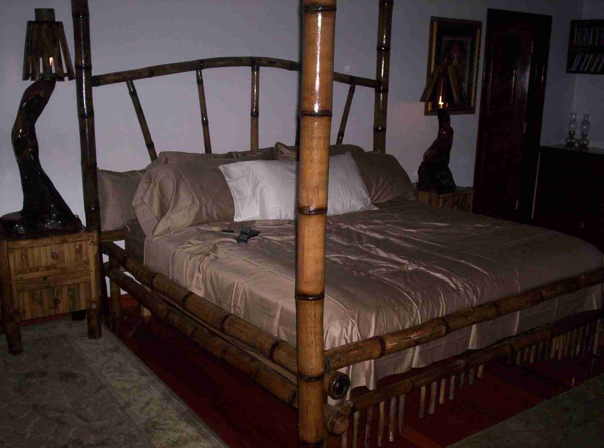 Four-poster bed with tall bamboo posts and a bamboo slat footboard