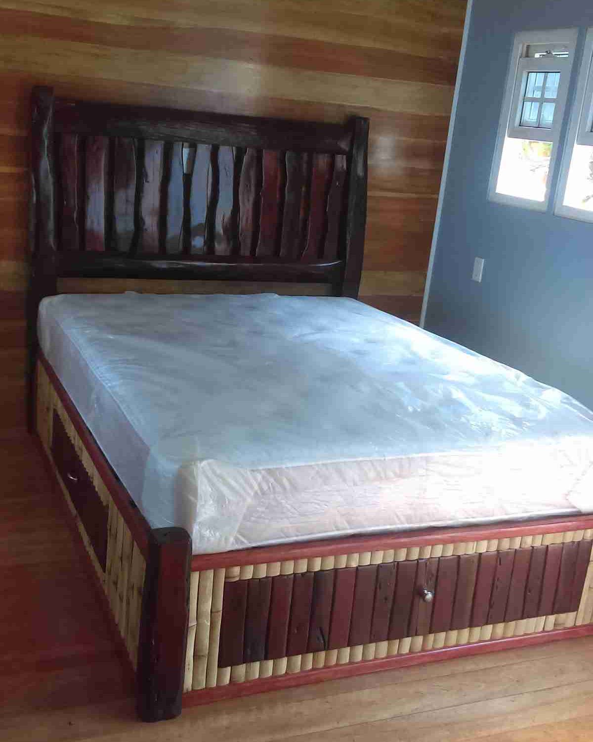 Bed with a dark logwood headboard and a bamboo slat base