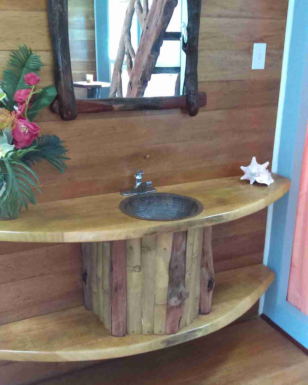 Bathroom vanity with a round basin on a half-round wood shelf and a bamboo post base