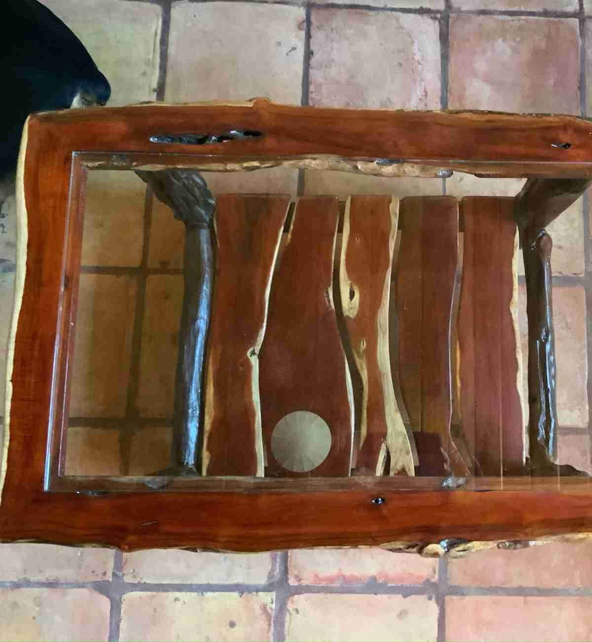 Glass-top center table resting on a carved logwood root base