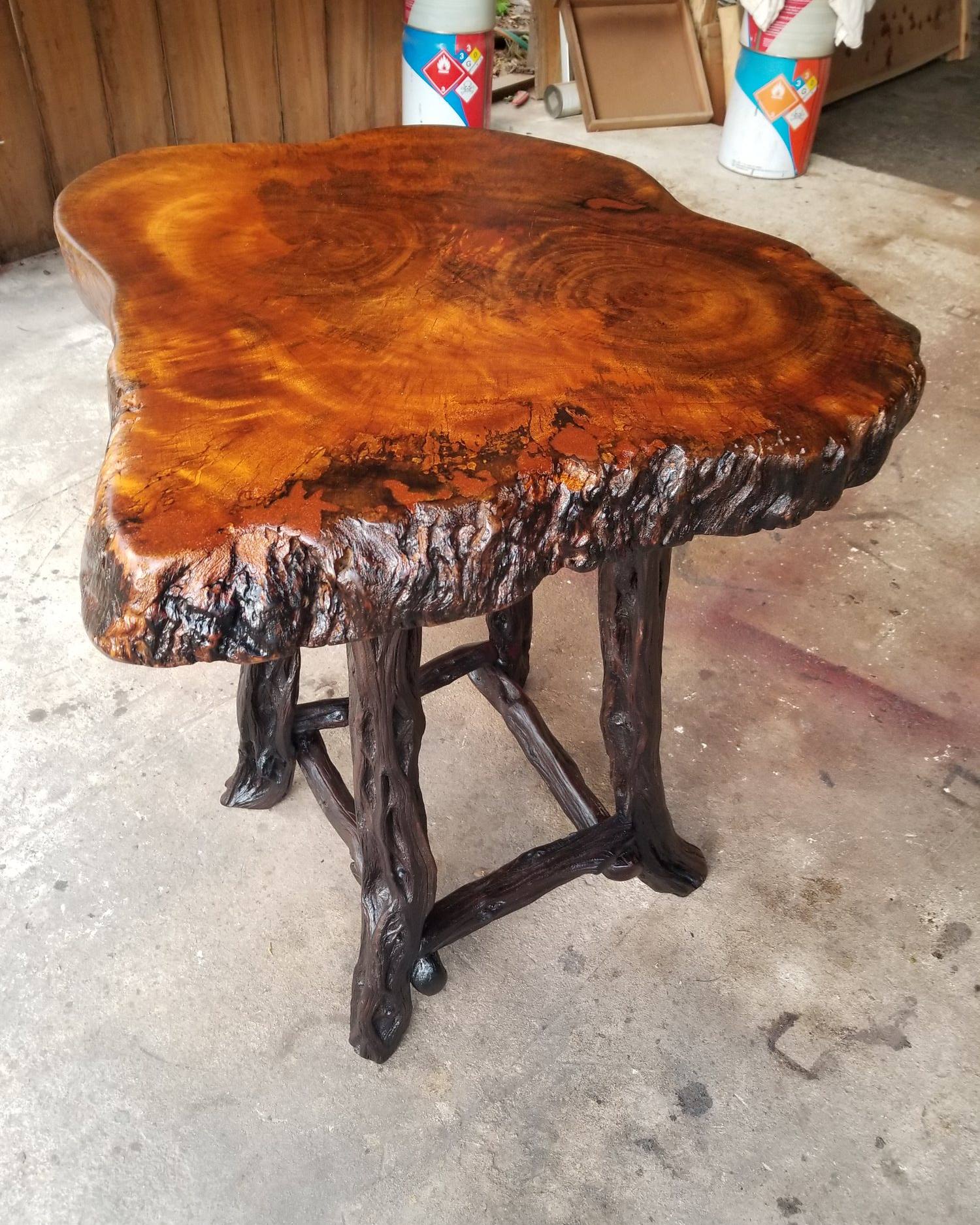 Polished live-edge burl slab table with glowing orange grain on dark logwood legs