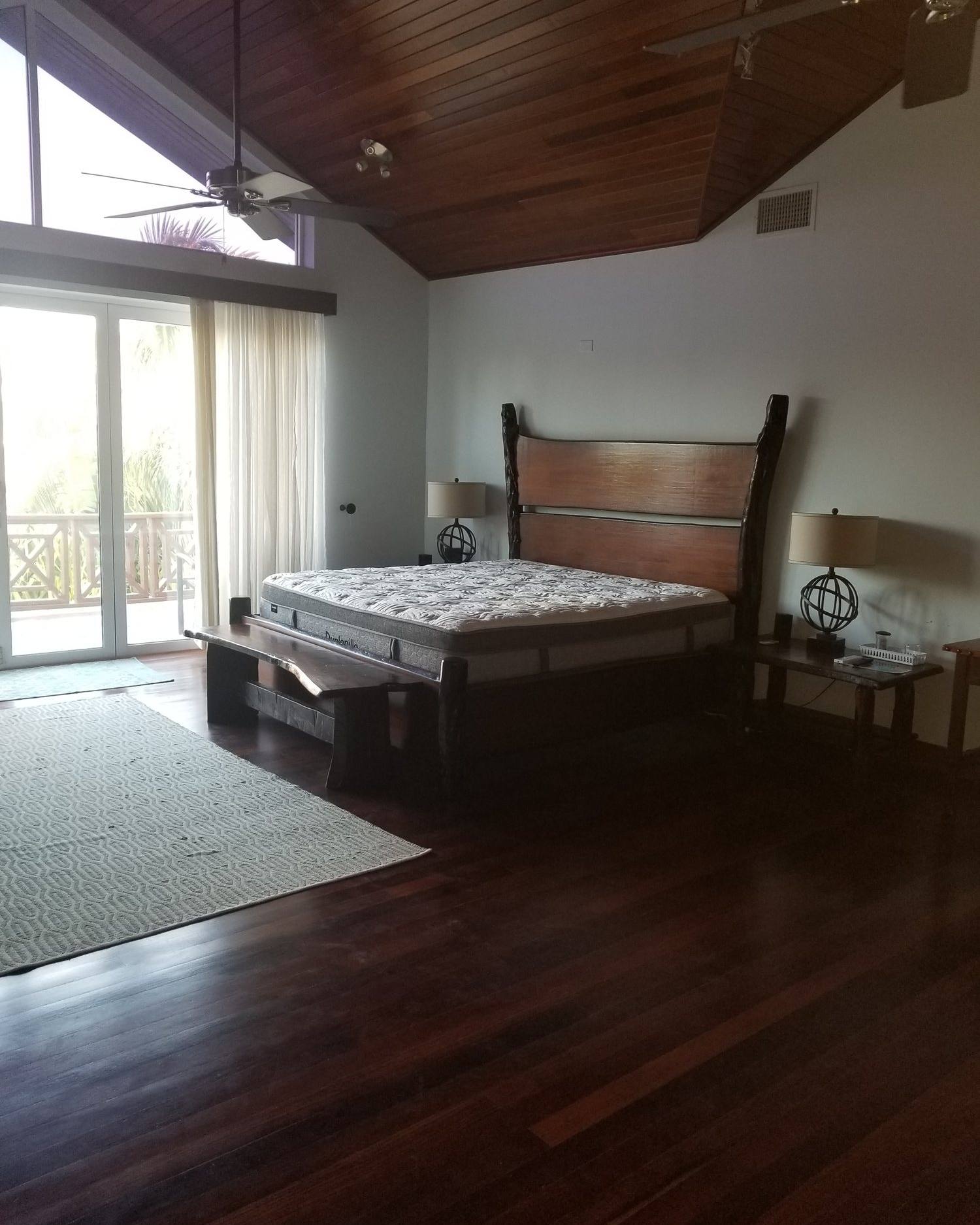 Bed with a solid mahogany panel headboard in a room with a wood-beamed ceiling