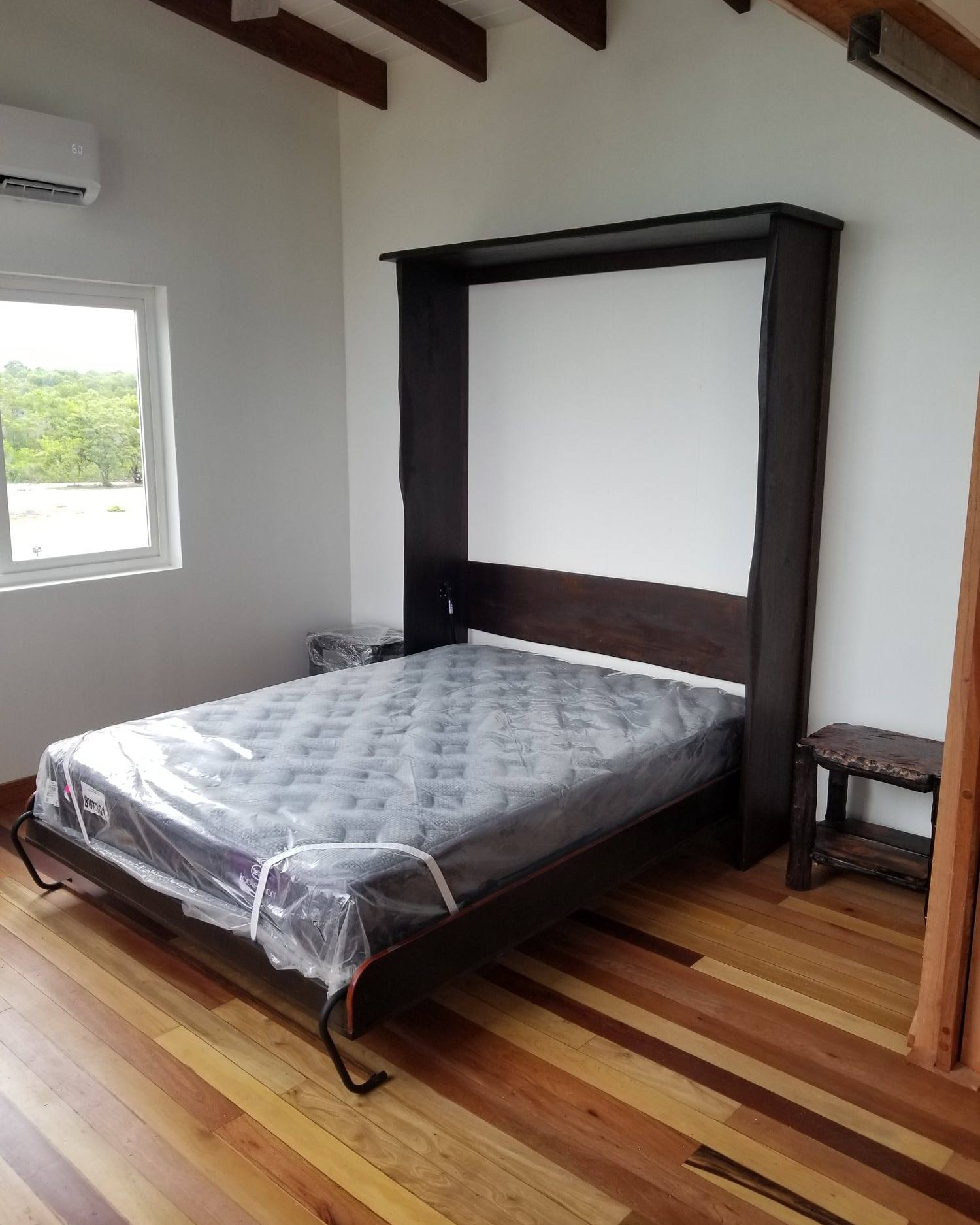 The mosaic Murphy bed folded down from its cabinet with a mattress in place