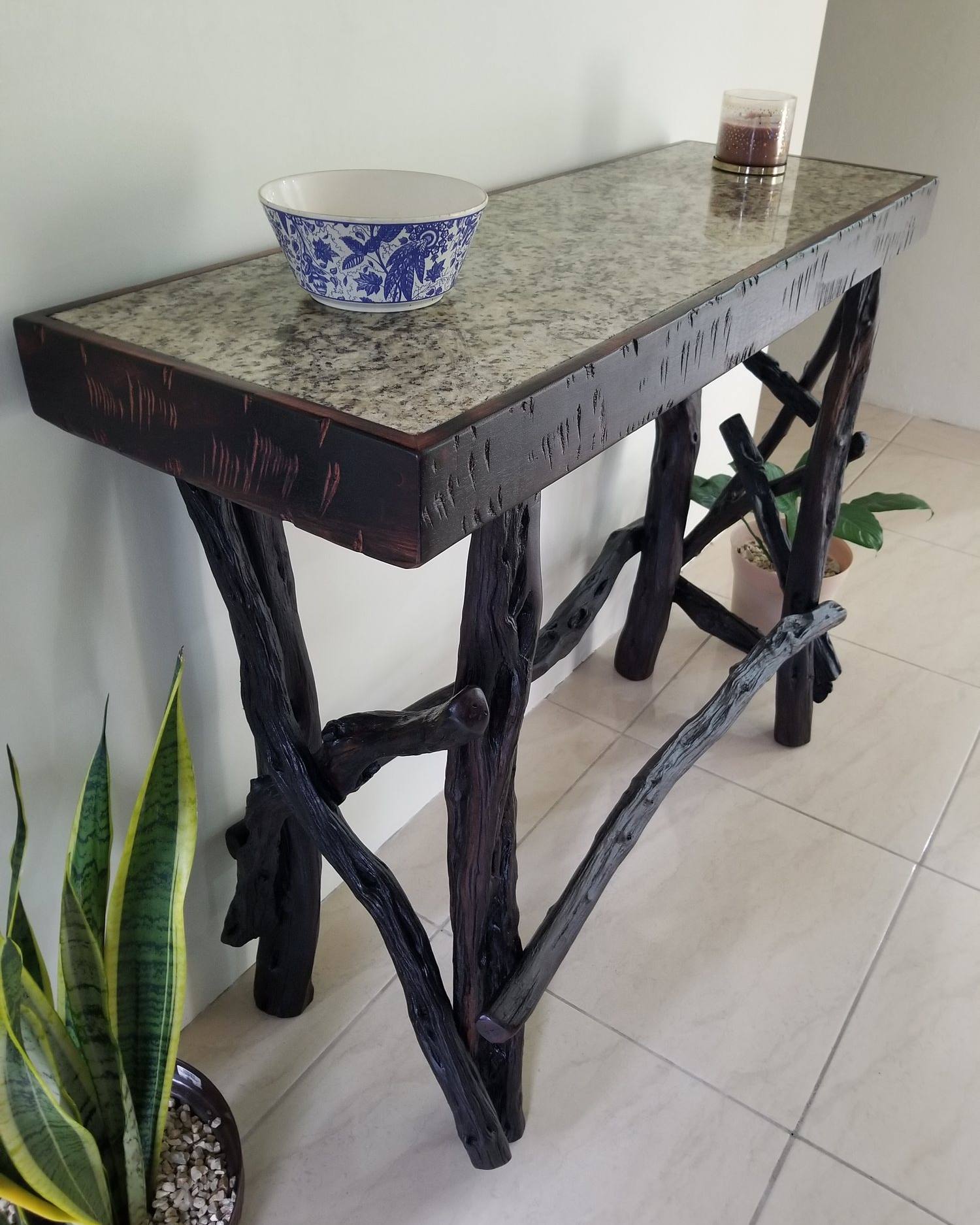 Console table with a stone top on crossed logwood branch legs